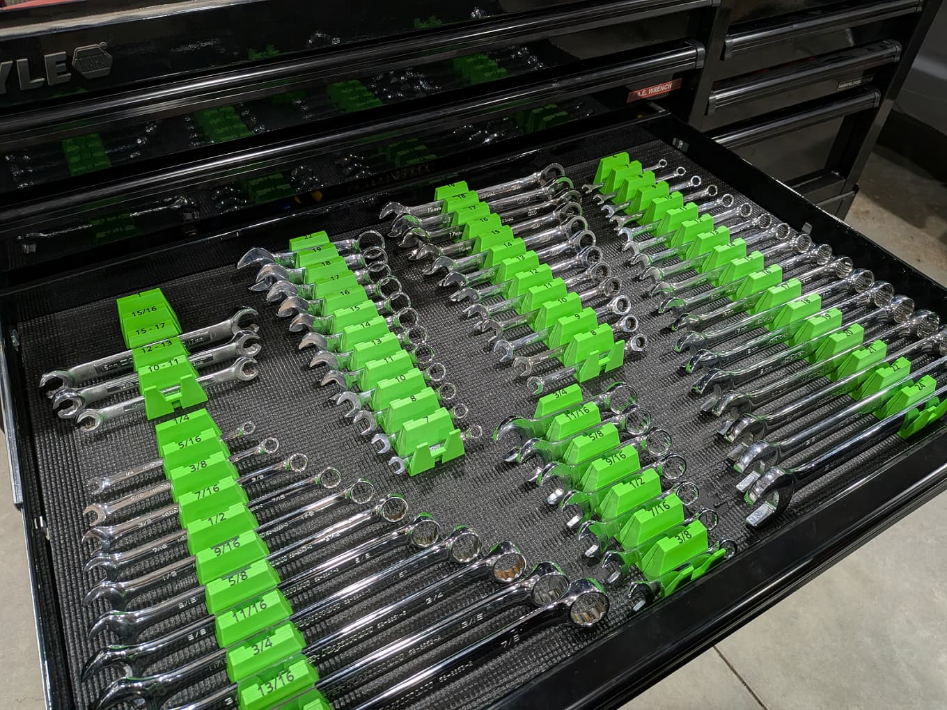 Open tool drawer with organized wrenches in green wrench holders on ablack tray.